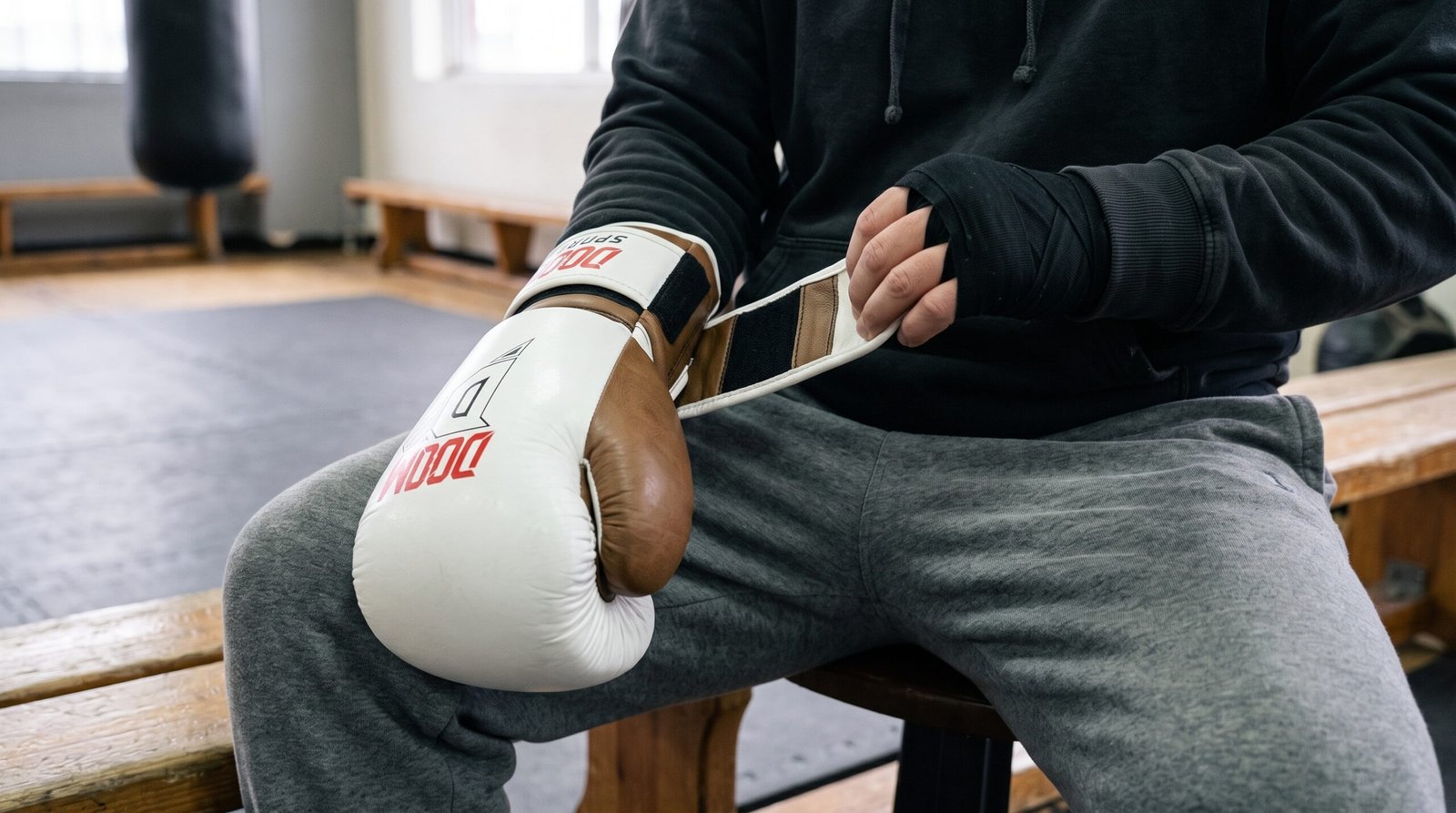 Seated boxer fastening the Velcro wrist closure of a DOOM K-1 STRIKER glove